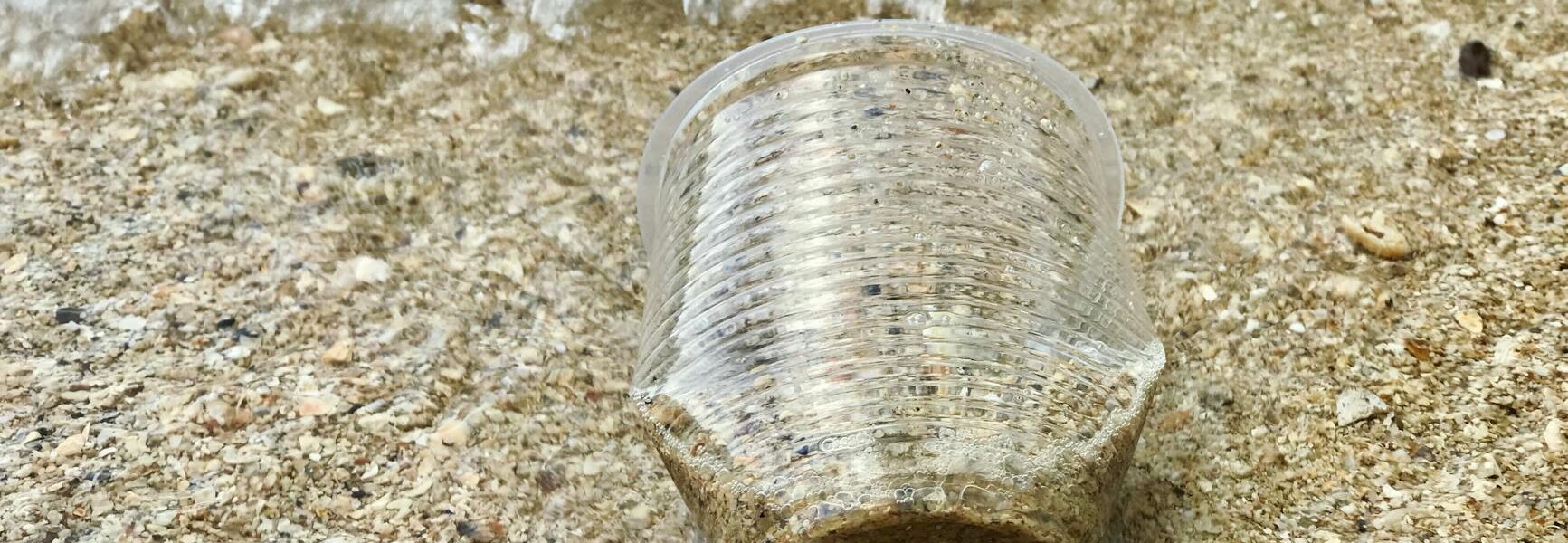 close up photo of plastic cup on sand
